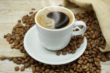 A Hot Cup of Strong and Flavored Coffee among Light Roasted Coffee Beans on a Wooden Table