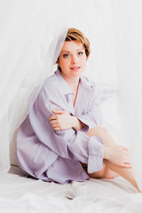 Pretty woman in man's shirt sitting in bed © OlgaKhorkova