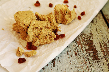 Sunflower halvah with raisin on white crumpled paper, on a wooden background