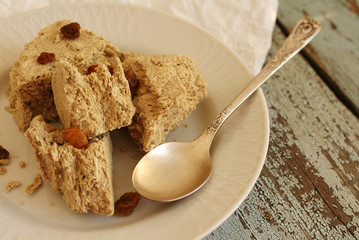 Sunflower halvah with raisin on a white plate, on a wooden background