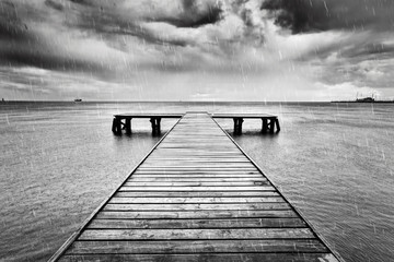 Oude steiger, pier aan zee. Zwart en wit, regen.