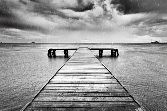 Fototapeta Old jetty, pier on the sea. Black and white, rain.