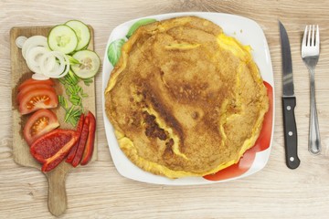 Scrambled egg omelet with vegetables on a wooden table. Preparation of fast food home.
