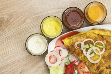 Scrambled egg omelet with vegetables on a wooden table. Preparation of fast food home.
