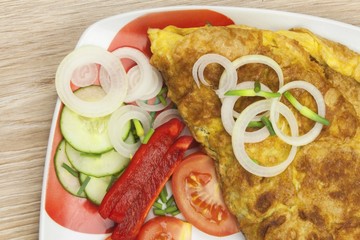 Scrambled egg omelet with vegetables on a wooden table. Preparation of fast food home.
