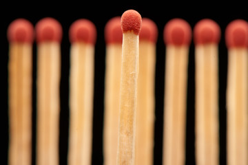 Red match standing in front of red wooden matches