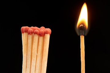 Group of red wooden matches standing with burning match