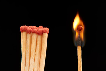 Group of red wooden matches standing with burning match