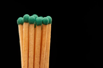 Group of green wooden matches isolated on black background