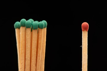Group of green wooden matches standing with red match