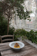 Piatto di pasta ai carciofi in un ristorante rustico con piante.