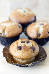 Four chocolate chip muffins on wooden tabletop
