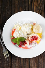 Fruit damplings with two strawberries and melissa leaves