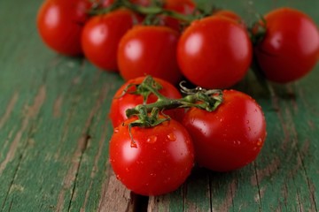 Three red juicy tomatoes on board with worn green color