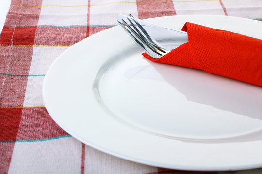 White plate, knife and fork on a red napkin