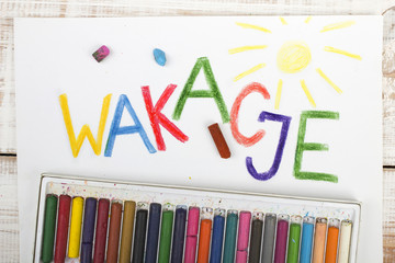 Polish word "wakacje" written in colored pencils