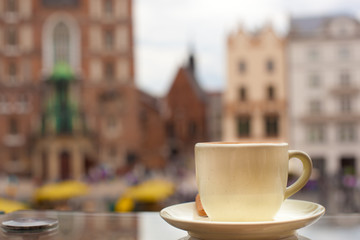 Cup of coffee on the balcony in front of the market square of Krakow