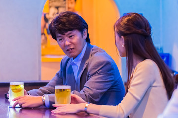 カウンターでお酒を飲むカップル   © Taku