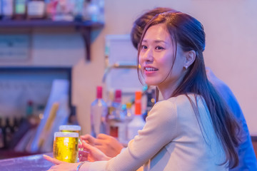 カウンターでお酒を飲むカップル   © Taku