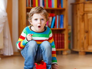 Funny blond kid boy shouting and playing, indoors