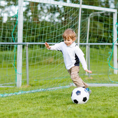 Two little sibling boys playing soccer and football on field