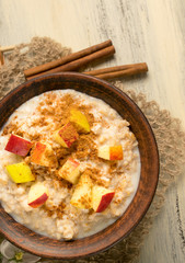 Oatmeal with apple and cinnamon in the bowl and cinnamon sticks