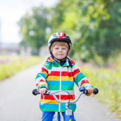 Fototapeta na wymiar Kid boy in helmet riding his first bike, outdoors