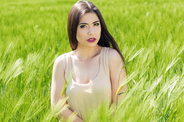 Naklejka na ściany i meble Beautiful girl at the green field of wheat