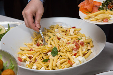Uomo che prende della pasta fredda su tavolo apparecchiato per buffet