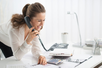 Happy businesswoman on telephone looking at document