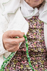 close up hands of a senior woman praying with prayer beads