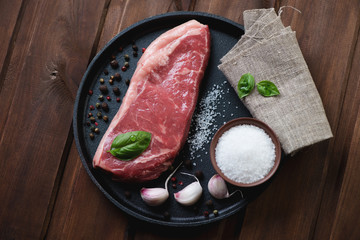 Raw black angus steak striploin with seasonings, view from above