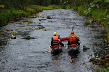 Two men on a catamaran raft down the taiga river.