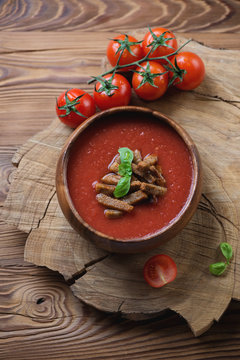 Gazpacho topped with croutons and basil over wooden background