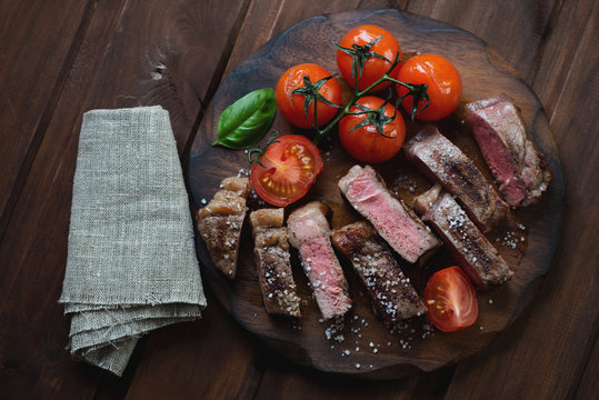 Sliced medium grilled striploin steak on a rustic wooden surface