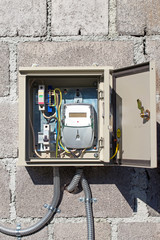 Fototapeta na wymiar The electricity meter in a protective metal casing on a stone wa