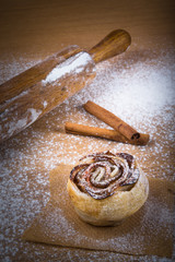 Homemade pastries with cinnamon on a light wooden table with flo