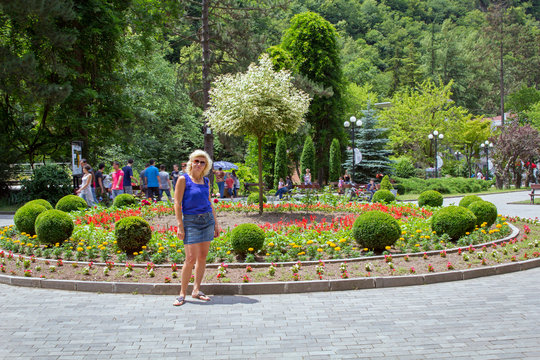 Slim blonde posing in summer city park
