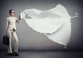 Young businesswoman with suitcase using spray