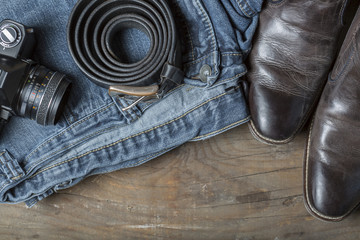 Vintage Kamera, Jeans, Leather Boots and Belt on wooden Background