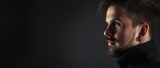 handsome brutal guy with beard on dark background