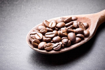 Coffee beans on wooden spoon.