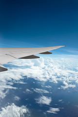 Wing of airplane flying above the clouds