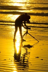 golden sunrise, silhouette of phtographer on the beach.