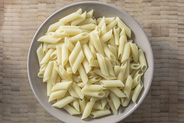 White pasta on a brown bowl wooden background top view