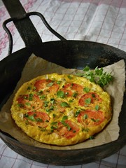 Omelet with tomatoes and basil on the black vintage pan