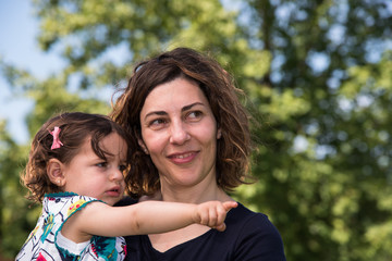 Fototapeta premium Mother with young daughter in arms, outdoors in park 