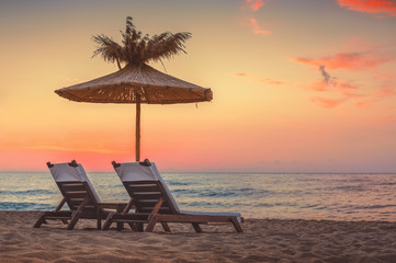 Vivid sunrise on a beautiful sandy beach with sunshade