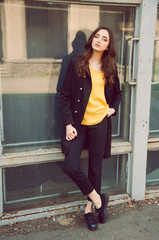 Obraz premium Young woman portrait in black trenchcoat and yellow blouse