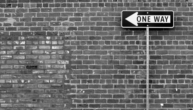 One Way Street Sign In Black And White With Brick Building 